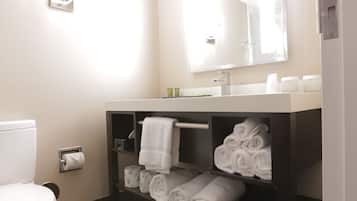 A bathroom with a toilet, sink, mirror, and towel rack.