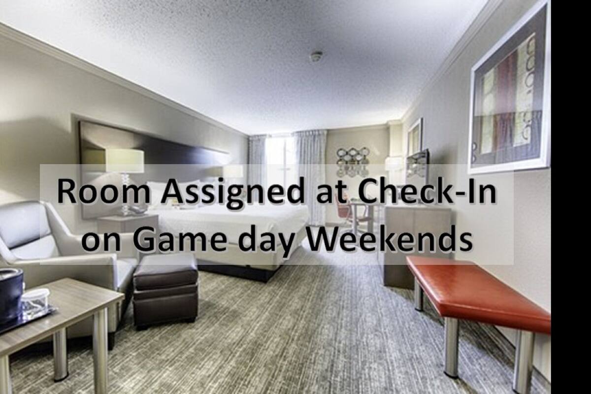 A hotel room with a bed, a desk, a chair, and a small table.