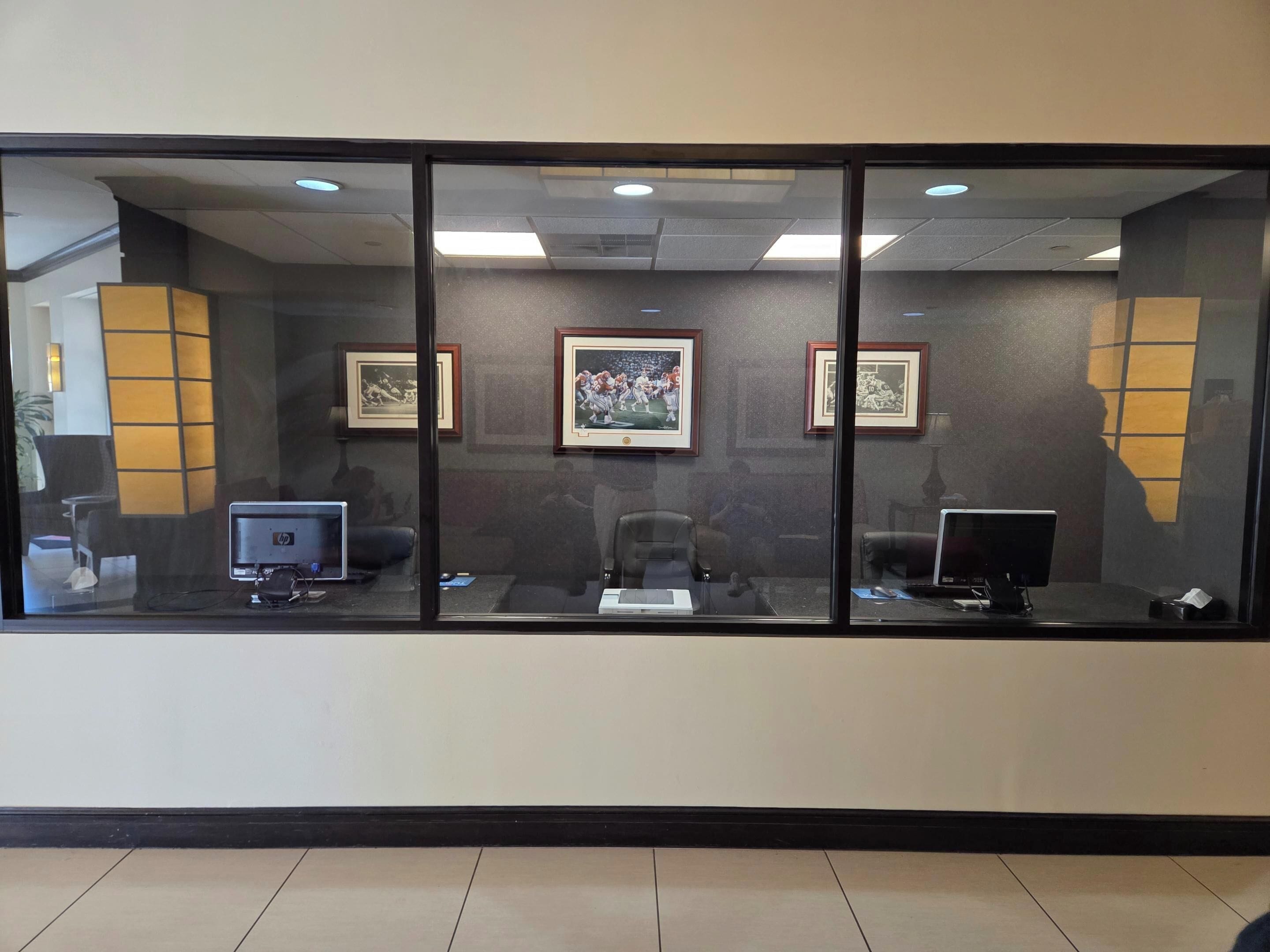 A reception area with a glass partition, framed pictures on the wall, and two HP computers on desks.