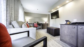 Habitación de hotel con sofá, escritorio, televisión de pantalla plana y kitchenette.
