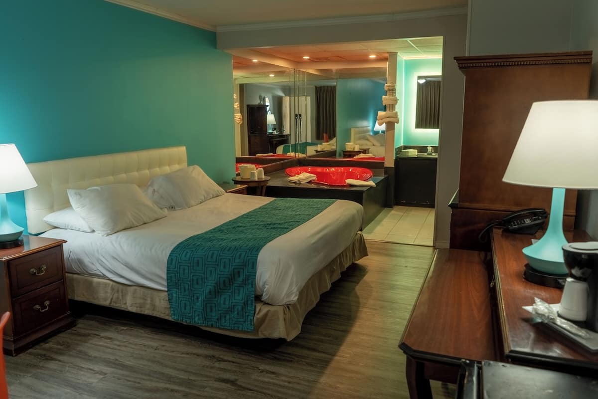 Ein Hotelzimmer mit Bett, Nachttischen, Schreibtisch und Spiegel.