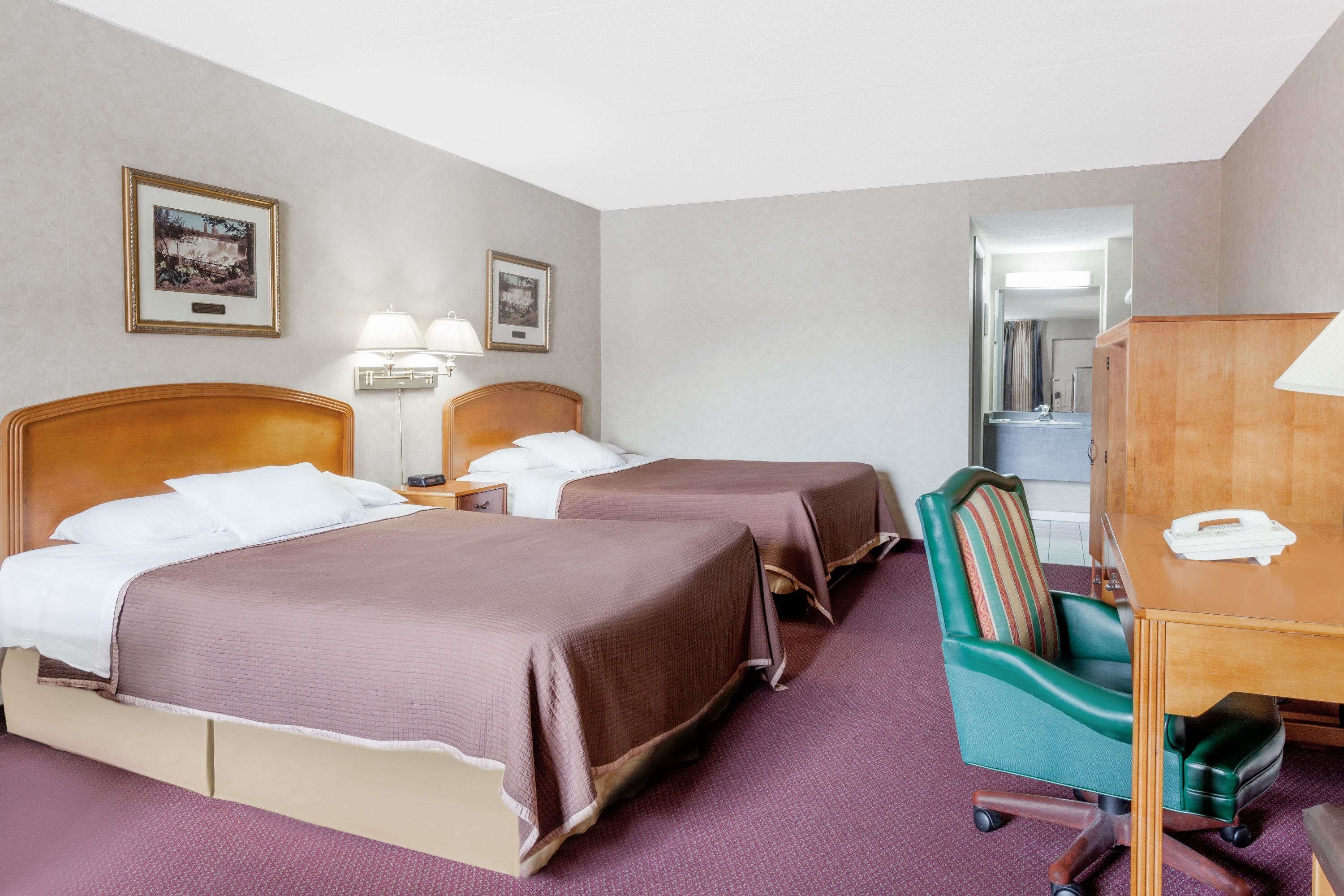 Et hotelværelse med to senge, et skrivebord, en stol og et spejl.