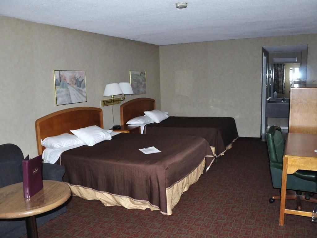 Une chambre d’hôtel avec deux lits, un bureau, une chaise et une petite table.