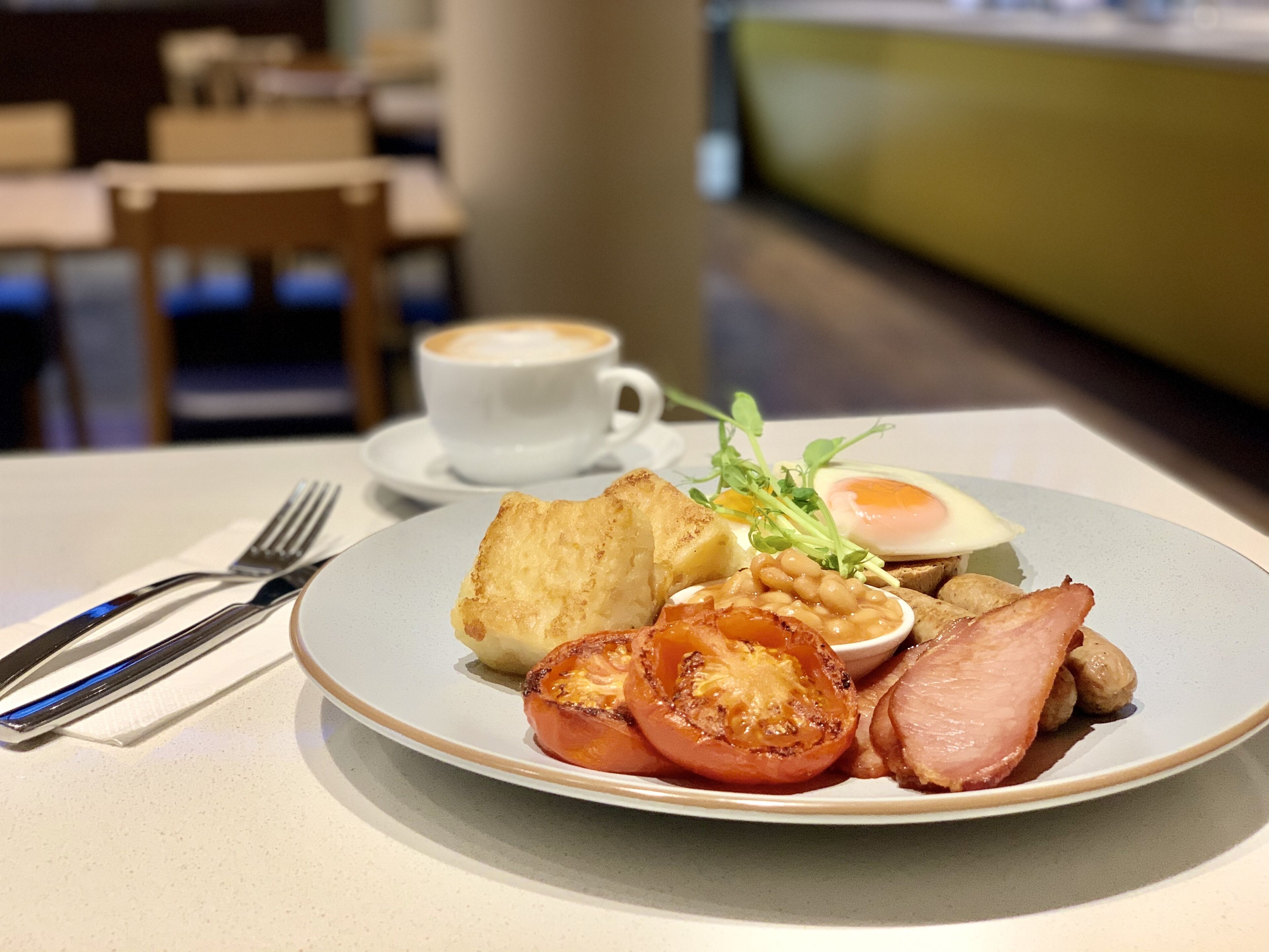 A breakfast plate with toast, eggs, tomatoes, beans, and ham.