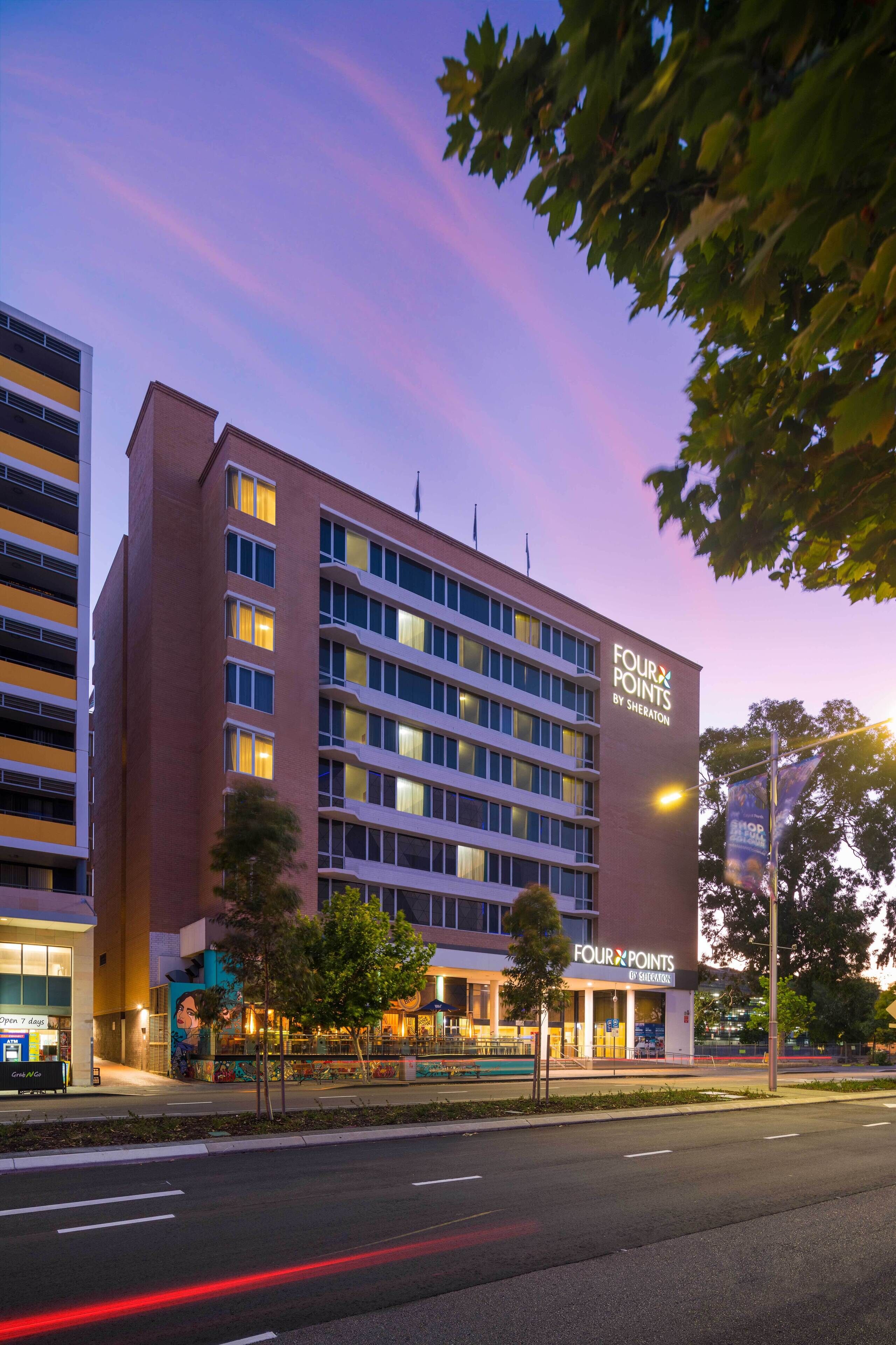 Ein Hotel mit moderner Fassade, mehreren Etagen und einer gut sichtbaren Beschilderung für 'Four Points by Sheraton'.