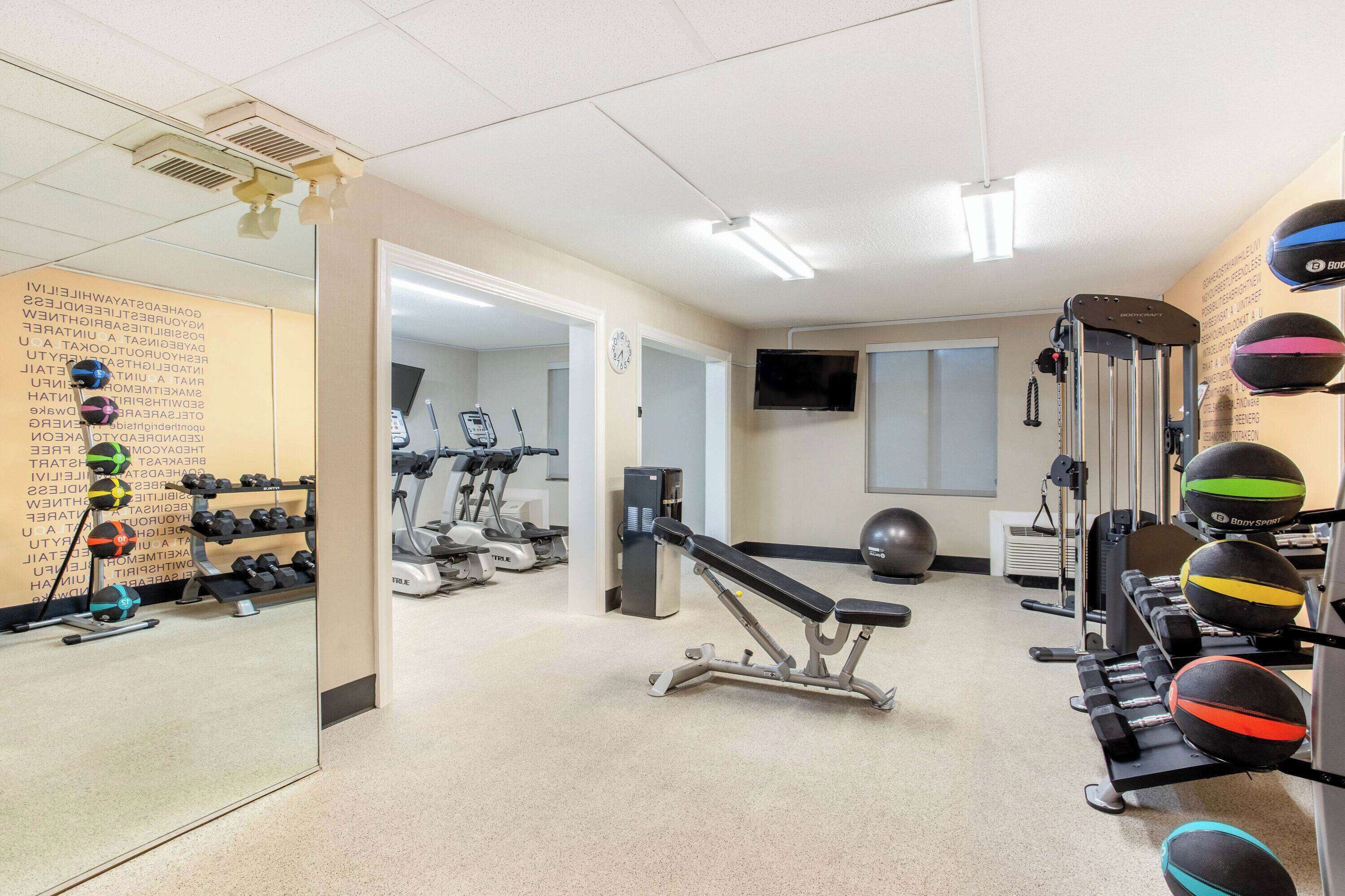 A gym with exercise equipment, a television, and a mirror.