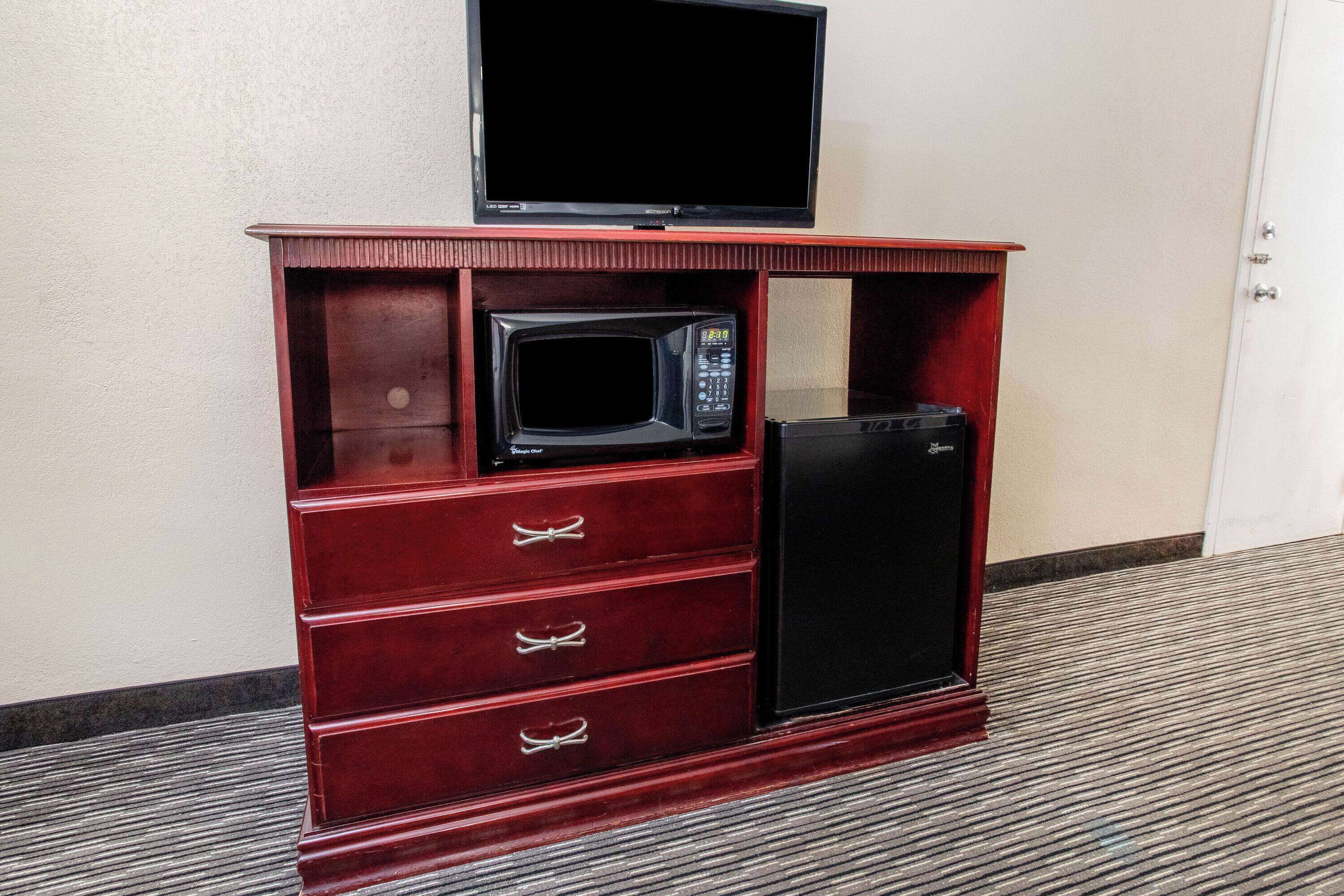 Un mueble de madera con televisor, microondas y refrigerador.