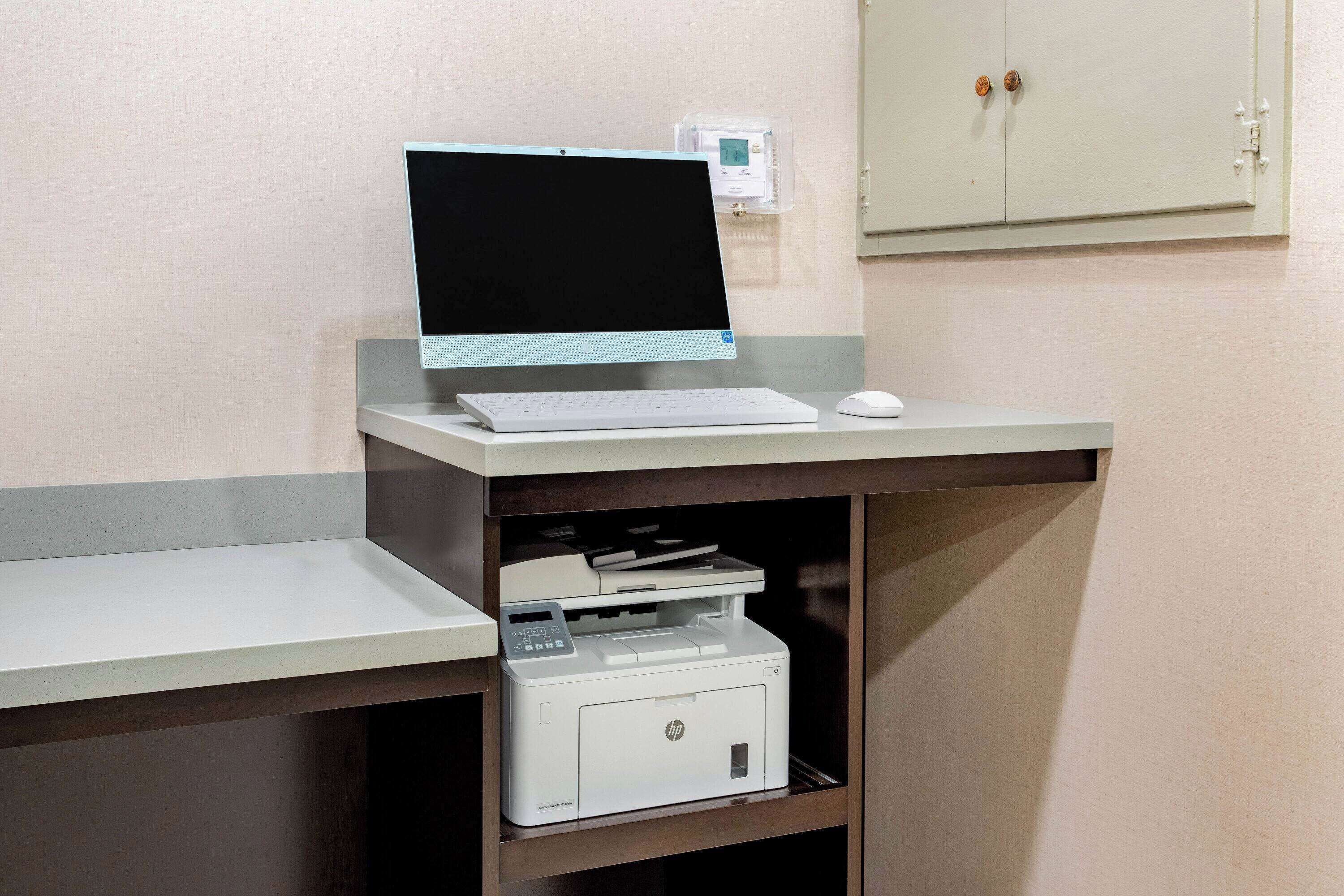 A desk with a laptop, a keyboard, a mouse, and a printer.