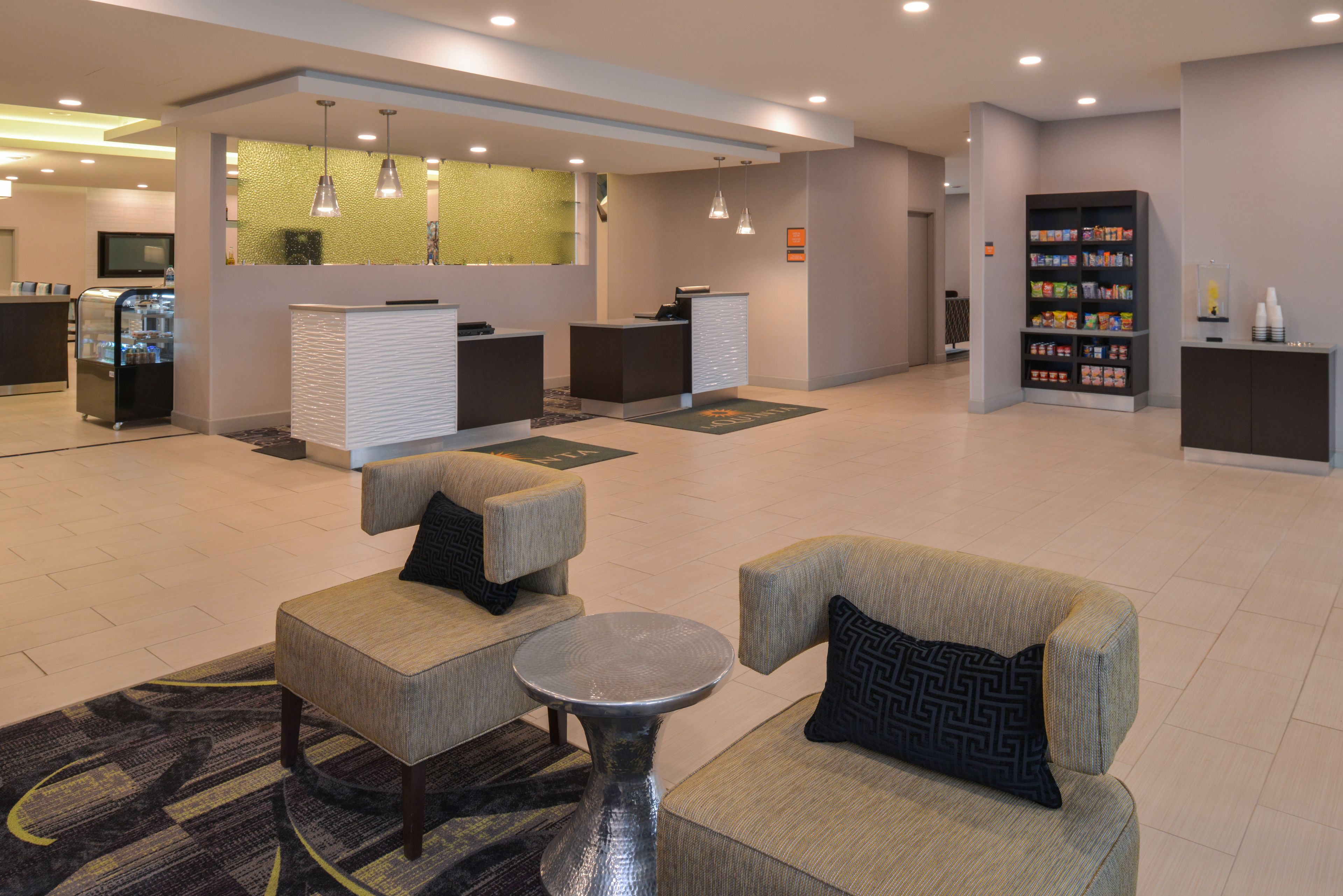 A lobby with seating, a reception desk, a refrigerator, and a snack bar.