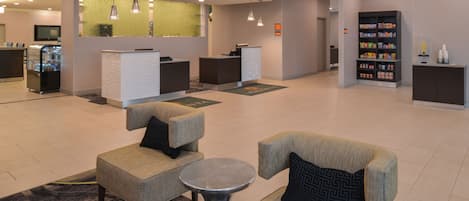 A lobby with seating, a reception desk, a refrigerator, and a snack bar.