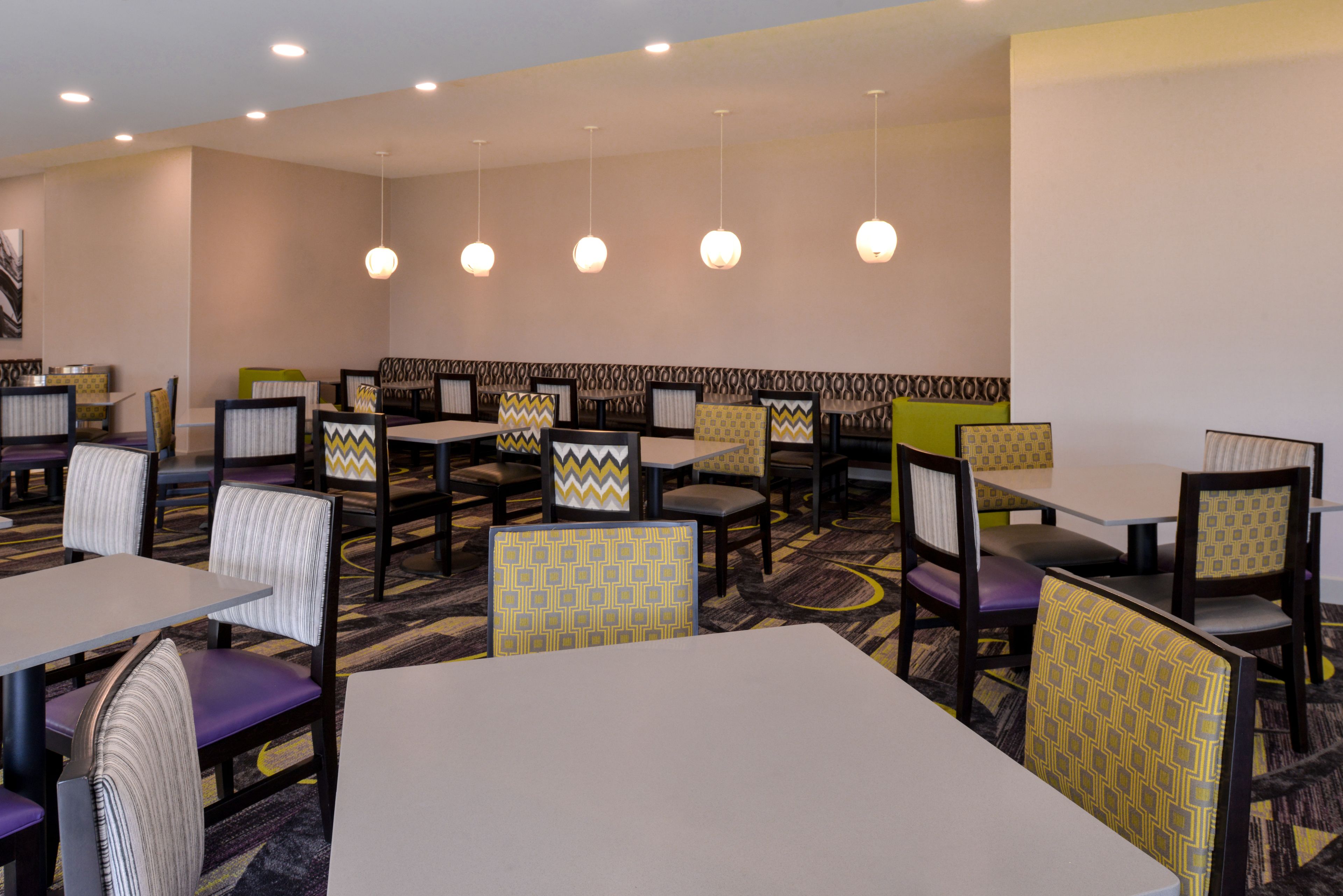 Un restaurante con varios reservados y mesas, que presenta tapicería con diseños y piso alfombrado.