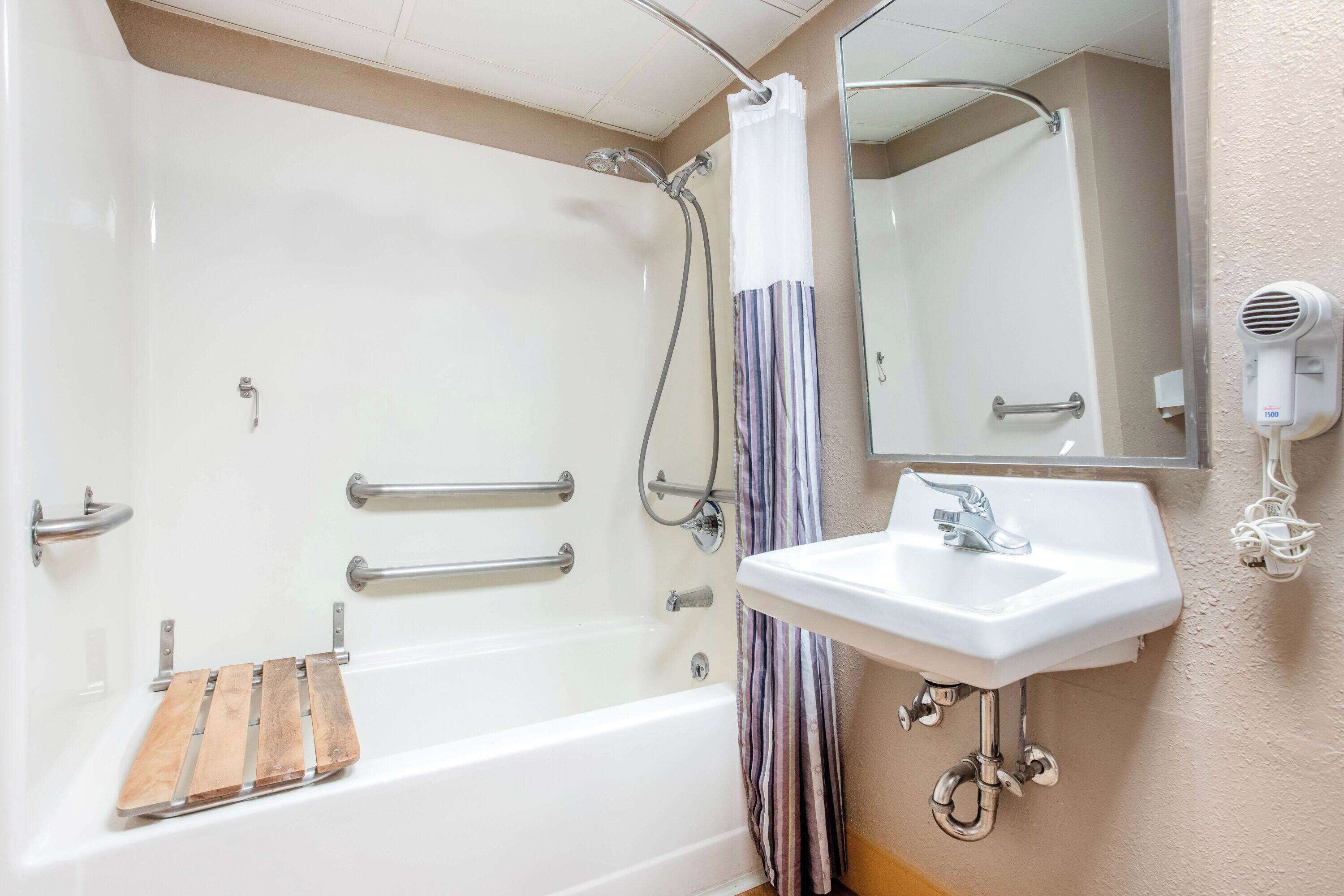 Un baño con bañera, ducha, lavamanos y secador de pelo.