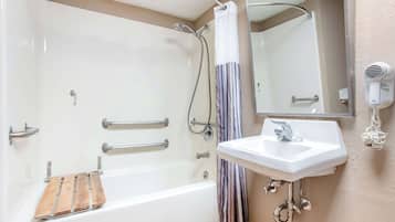 Un baño con bañera, ducha, lavamanos y secador de pelo.