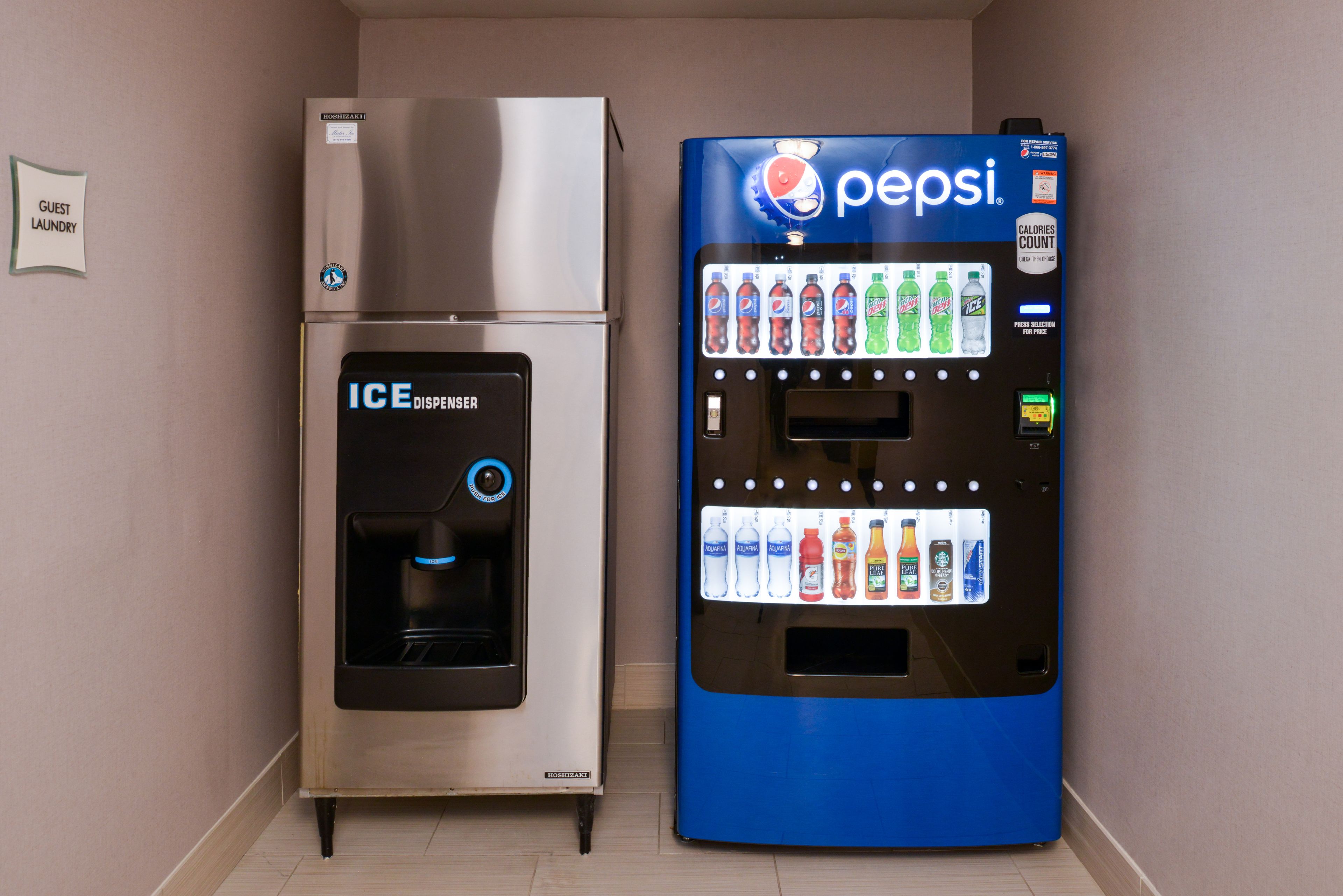 Habitación de hotel con minibar, señal de lavandería para huéspedes y máquina expendedora de Pepsi.
