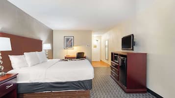 Een hotelkamer met een groot bed, een bureau met lamp, een televisie op een standaard en een dressoir.