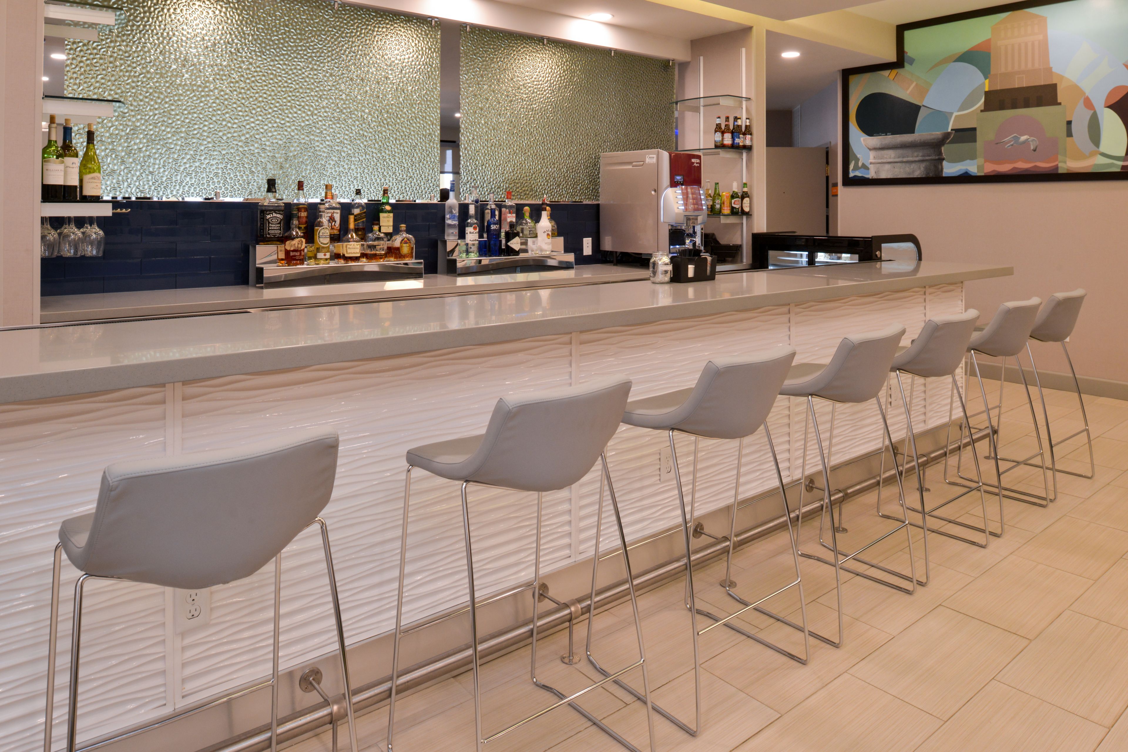 A bar area with a counter, bar stools, and a decorative wall.