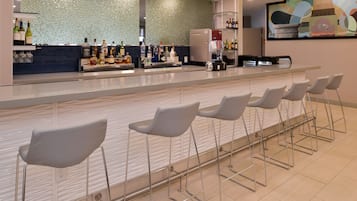 Un espace bar comprenant un comptoir, des tabourets de bar et un mur décoratif.