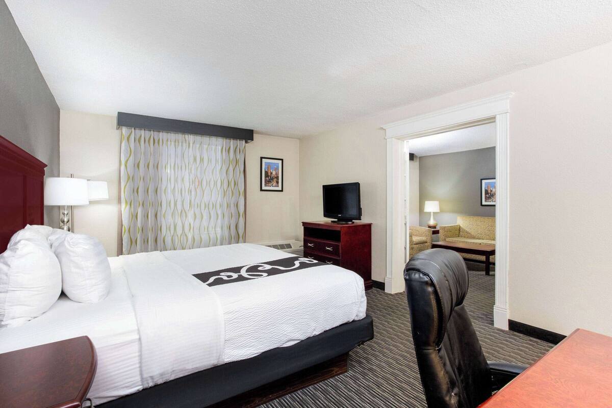 Ein Hotelzimmer mit einem Bett, einem Schreibtisch, einem Sessel, einem Fernseher und einer Couch.