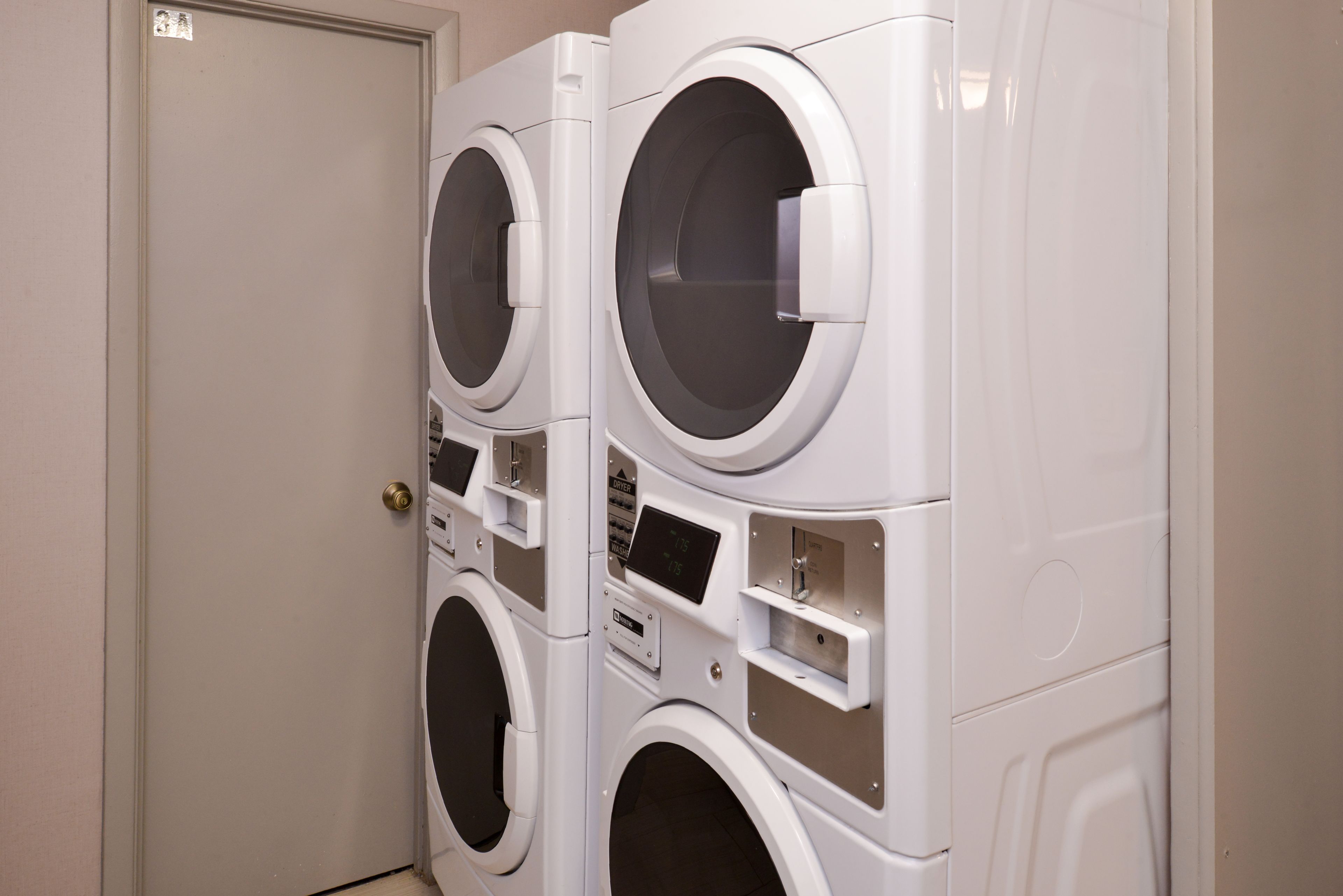 A row of stacked front-loading washing machines in a laundry room.