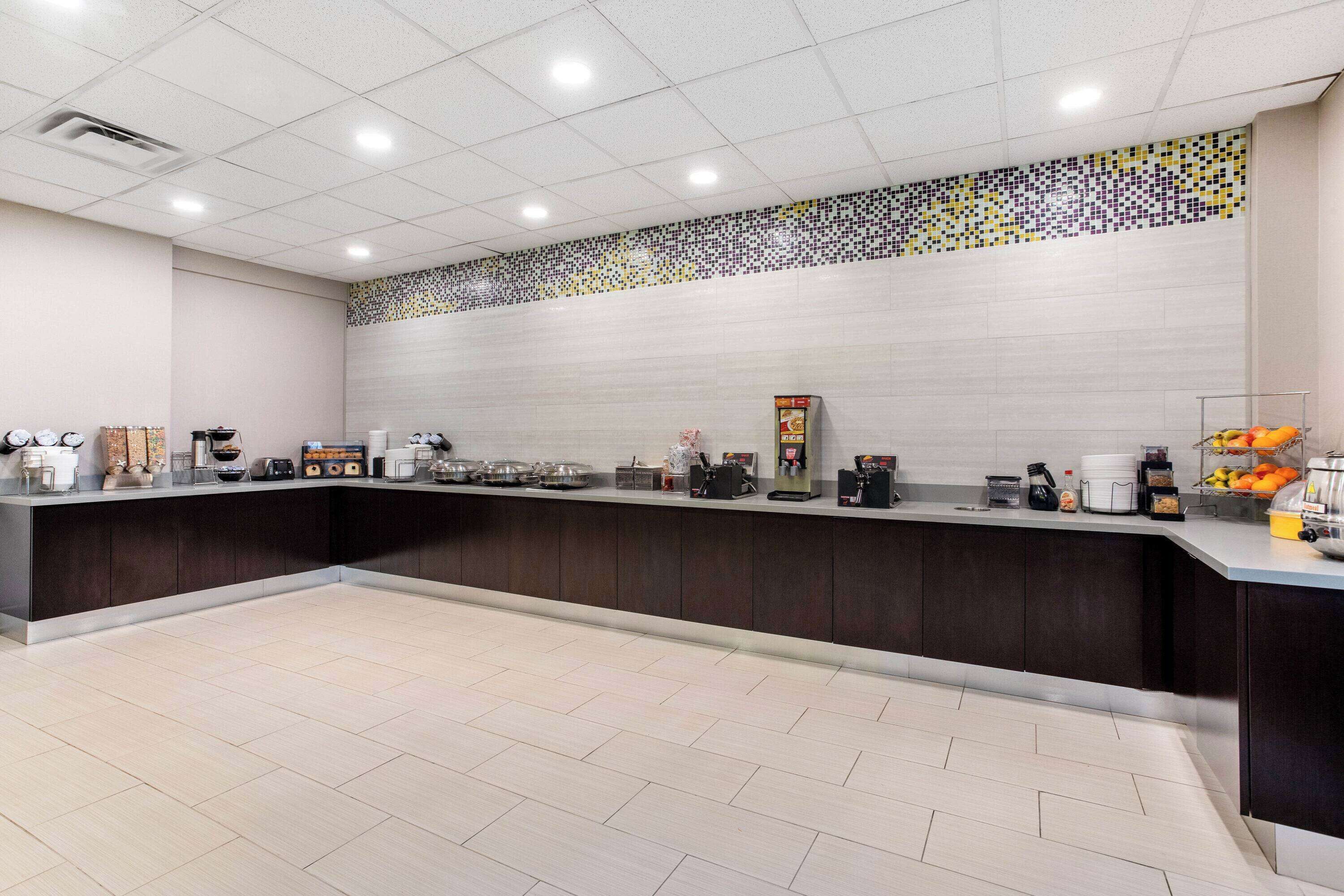 A spacious, modern kitchen area with a long counter, equipped with various appliances and a coffee station.