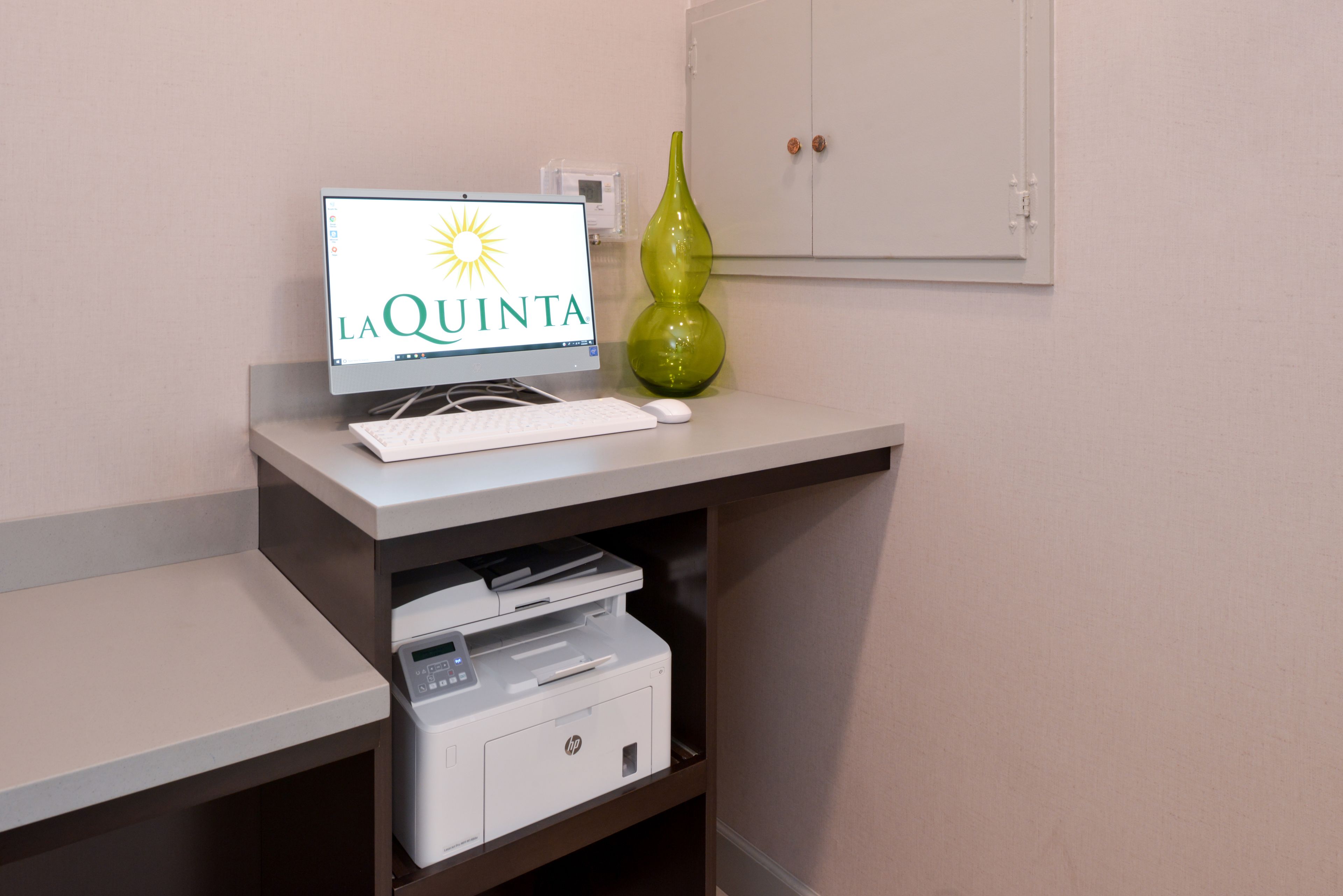 A computer monitor with a logo, a keyboard, a mouse, and a printer on a desk.