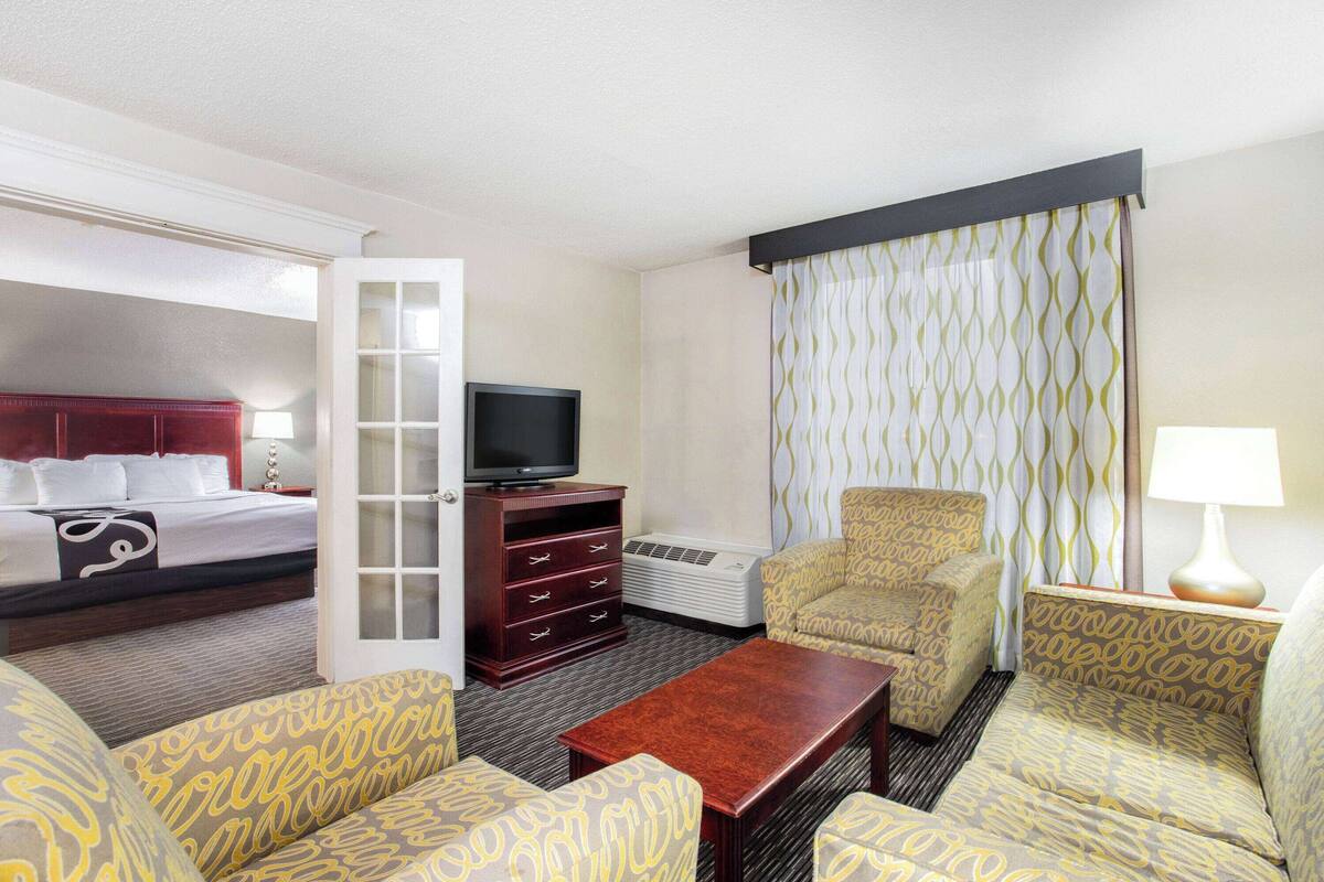 Ein Hotelzimmer mit Bett, Fernseher, Schreibtisch, Stuhl und Sofa.
