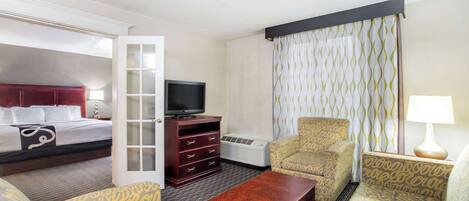 A hotel room with a bed, a TV, a desk, a chair, and a sofa.