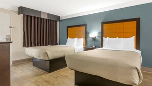 A hotel room with two beds, a desk, and a nightstand with a lamp. - Quality Inn & Suites North Charleston - Ashley Phosphate (North Charleston)