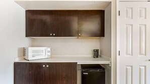 A compact kitchen with dark wooden cabinets, a white countertop, a microwave, and a black dishwasher. - Quality Inn & Suites North Charleston - Ashley Phosphate (North Charleston)