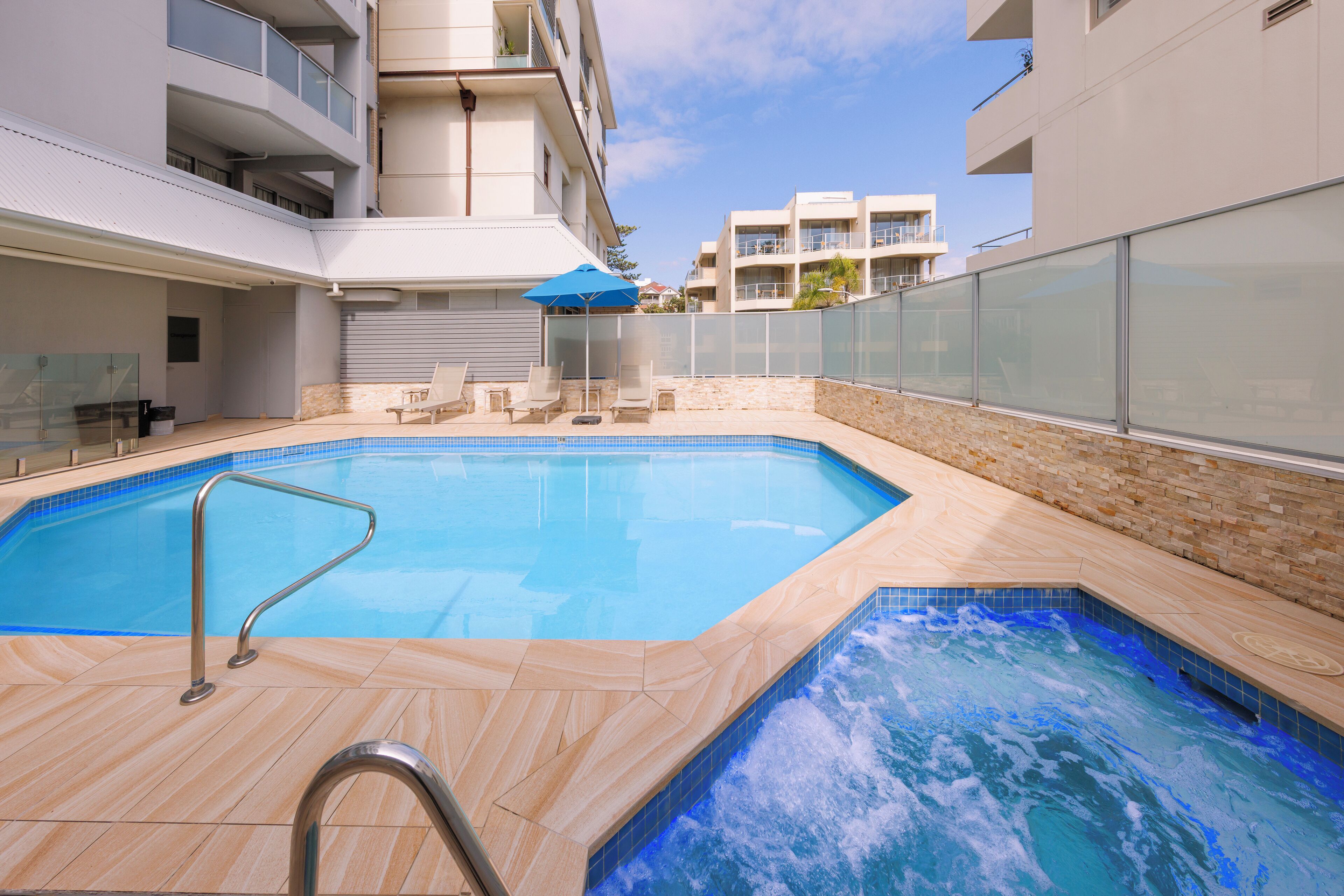 Una piscina interior moderna con vistas despejadas de los edificios circundantes y barandilla de vidrio.