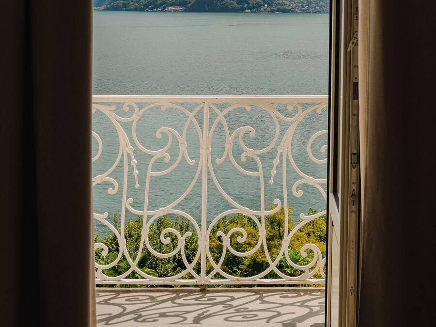 Un balcone con ringhiera in metallo che si affaccia su un lago e montagne.