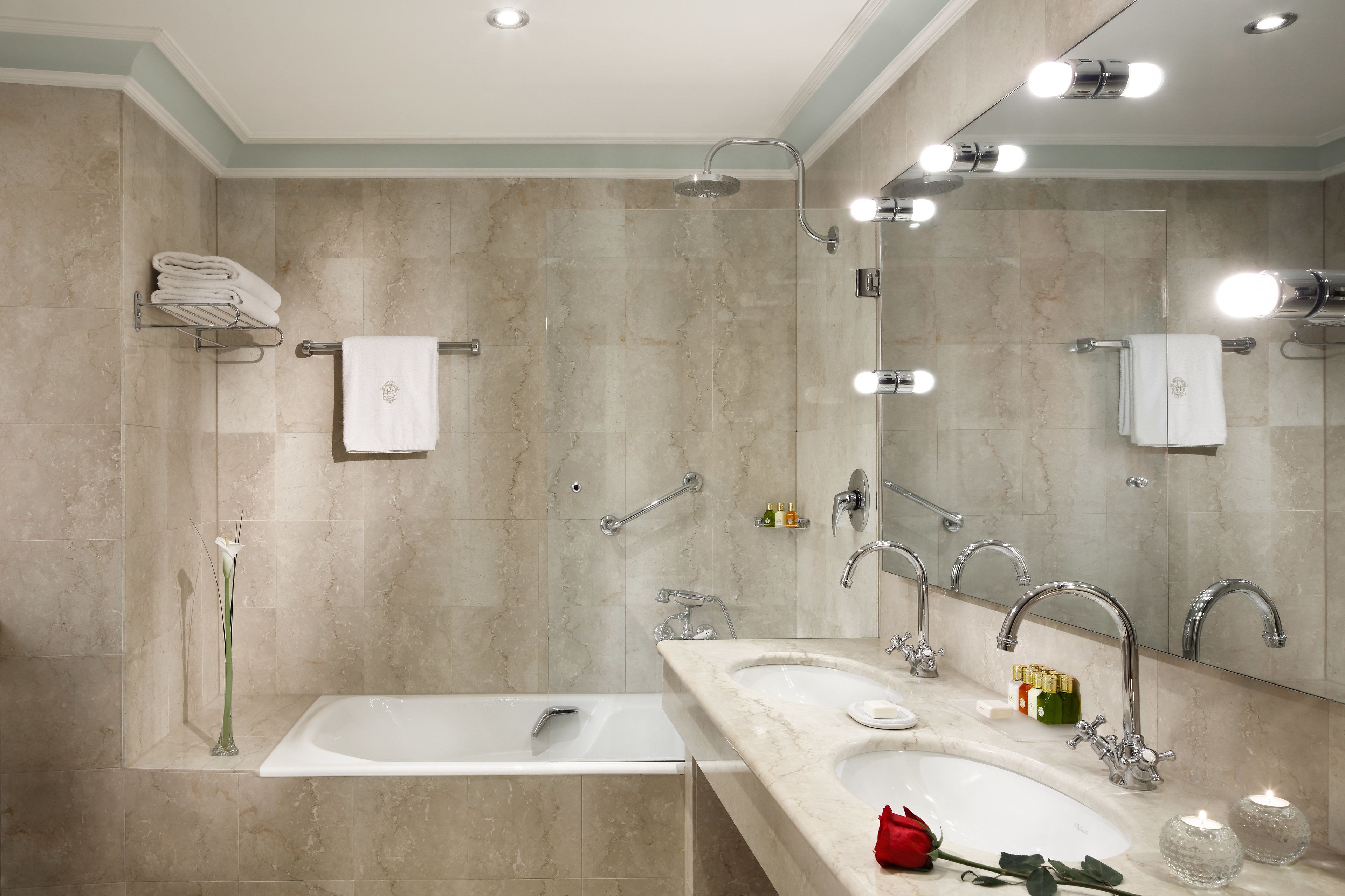 A modern bathroom with a bathtub, two sinks, a large mirror, and a shower.