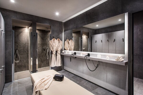 A modern bathroom with a large mirror, towel racks, and a bench with a bag.