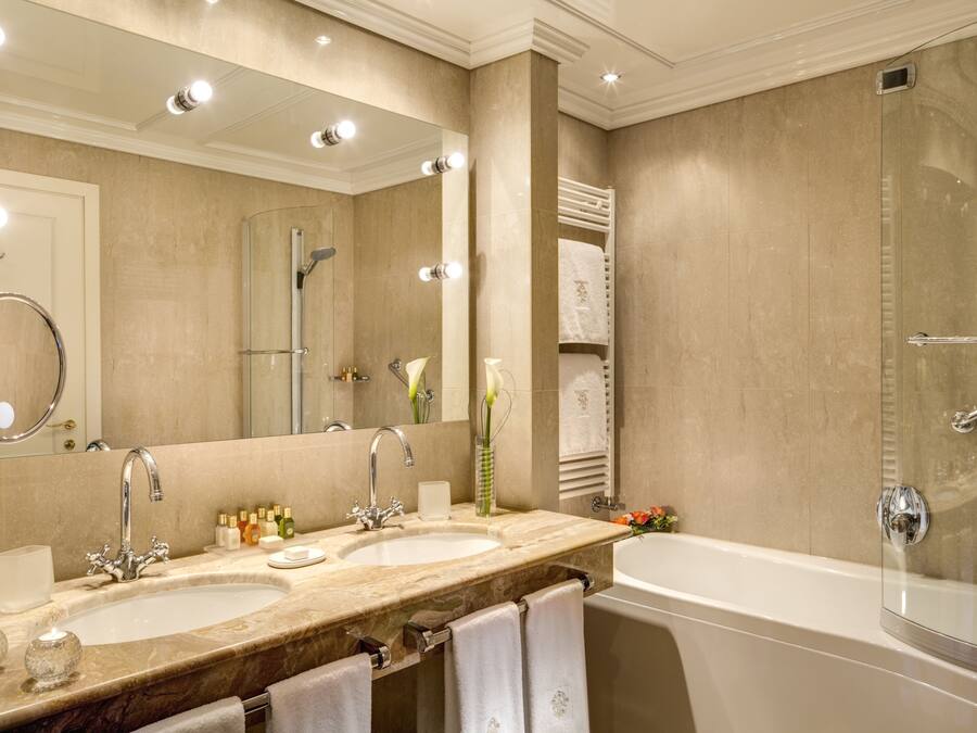 Un baño con dos lavamanos, un espejo grande, una bañera y un perchero para toallas.