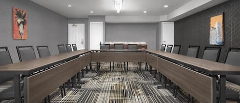 Un salón de conferencias con una larga mesa, sillas y una alfombra estampada.