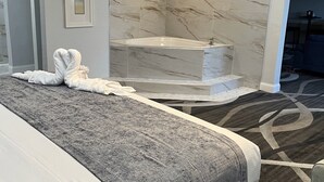 A hotel room with a large bed, a bathtub, and a carpeted floor. - Opal Hotel & Suites (Altamonte Springs)
