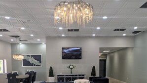 A modern lobby with a tufted white chair, a black sofa, and a chandelier. - Opal Hotel & Suites (Altamonte Springs)