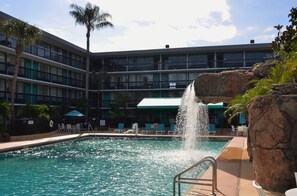 A hotel pool with a water feature, lounge chairs, and a palm tree. - Opal Hotel & Suites (Altamonte Springs)