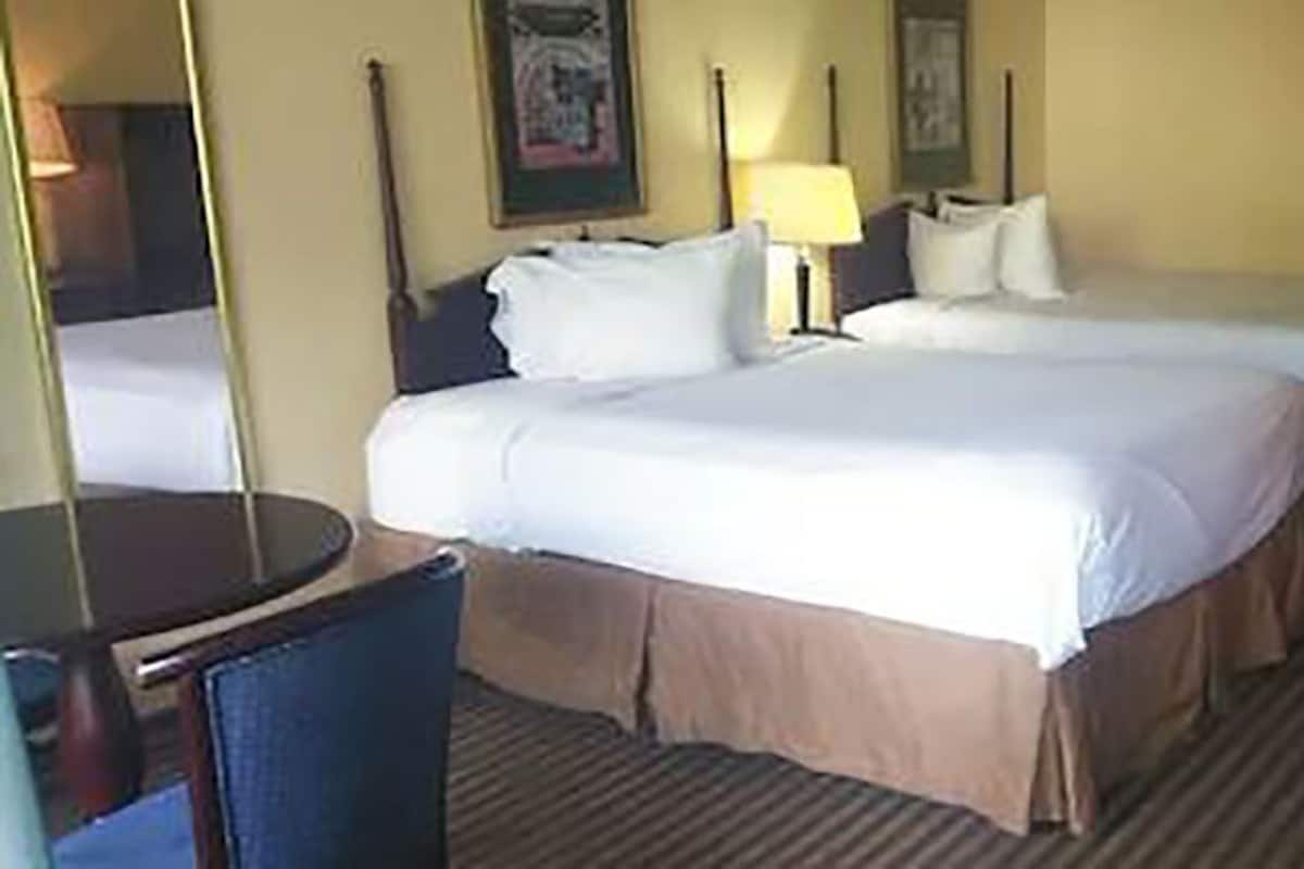 Una habitación de hotel con dos camas, un escritorio y una silla.