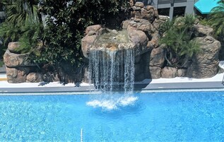 Una piscina al aire libre, sombrillas, sillones reclinables de piscina