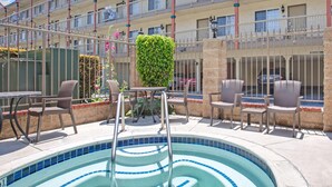 Une piscine avec des marches, entourée d’un espace de détente extérieur et d’un immeuble à plusieurs étages doté de balcons.