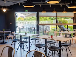 Un comedor interior con mesas y sillas, ventanas amplias y vistas al exterior.