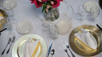 A table set for a formal meal with plates, cutlery, and a vase of flowers.