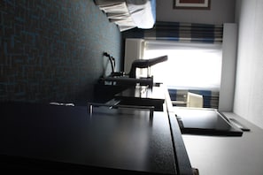 Quarto com cama, escrivaninha e janela com persianas.