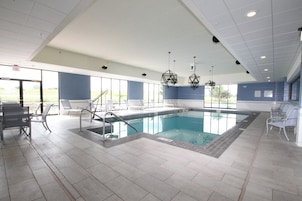 Una piscina con solárium empedrado, sillones de descanso y vistas al exterior.