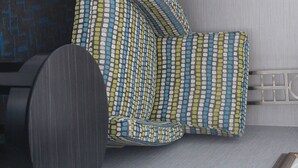 A modern sofa with a geometric pattern, a dark circular object, and a metal railing. - Holiday Inn Express Janesville - I-90 & US Hwy 14 by IHG (Janesville)