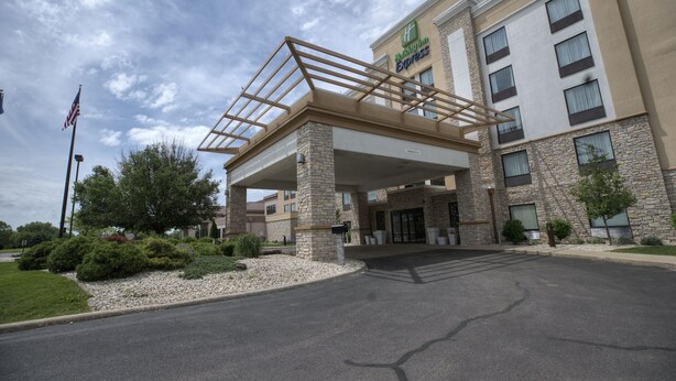 A Holiday Inn Express building with a stone facade, a covered entrance, and a flagpole. - Holiday Inn Express Janesville - I-90 & US Hwy 14 by IHG (Janesville)