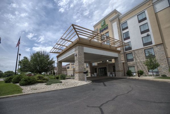 A Holiday Inn Express building with a stone facade, a covered entrance, and a flagpole.