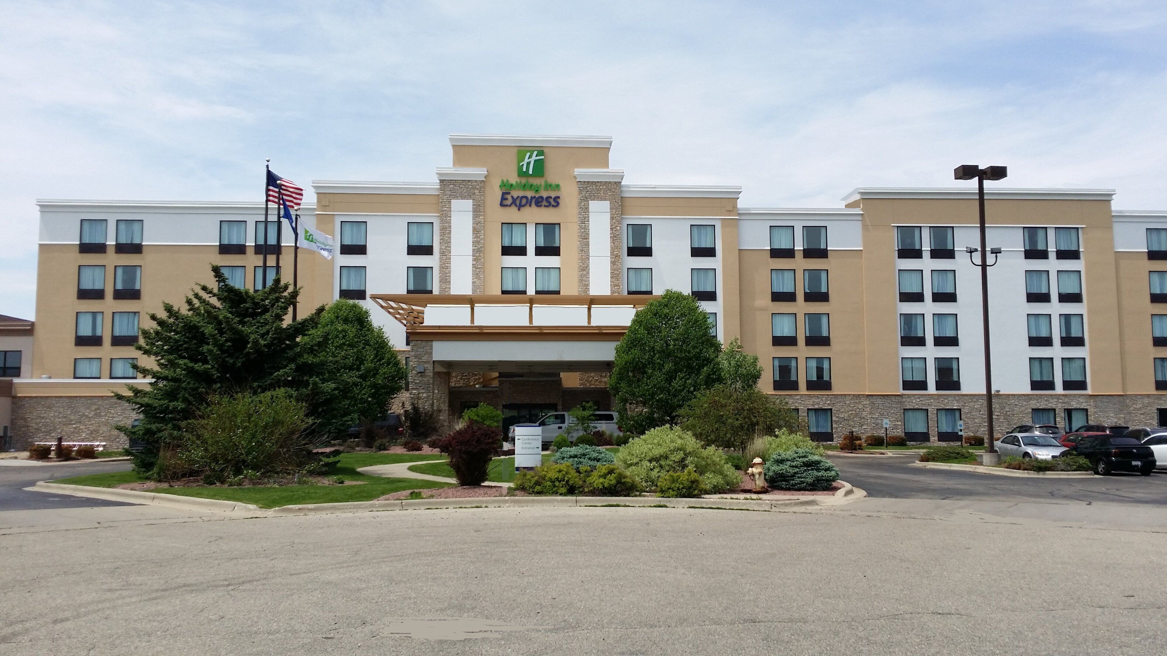 Un hotel Holiday Inn Express con entrada principal, varios pisos y estacionamiento.