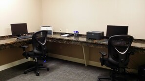 Un espacio de trabajo con dos monitores, una impresora y sillas de oficina.